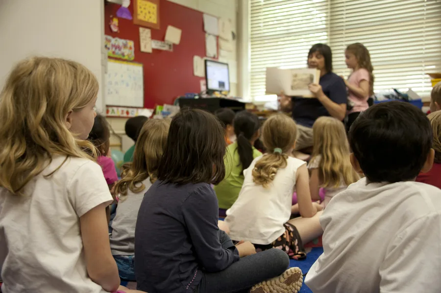 Children sitting together while a mentor explains a project