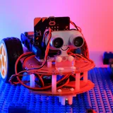 A red robot with an ultrasonic sensor on a blue brick base