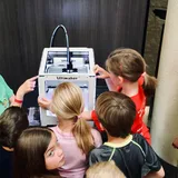 Children gathered around a 3D printer