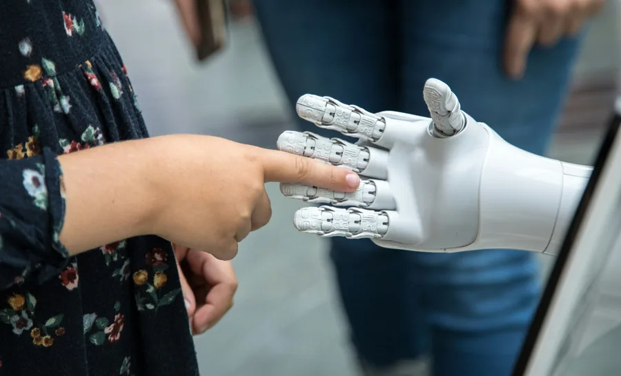 A child pointing at the fingers of a white robot hand